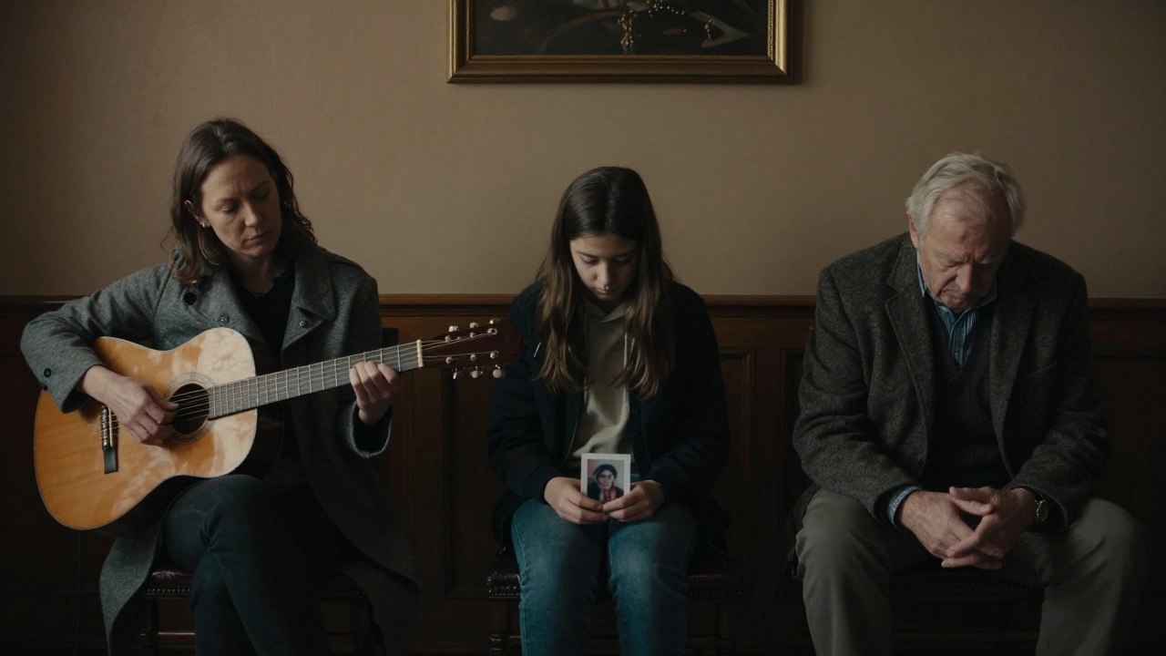 A woman playing guitar in a quiet funeral home lounge as three grieving individuals sit alone in lamplight.