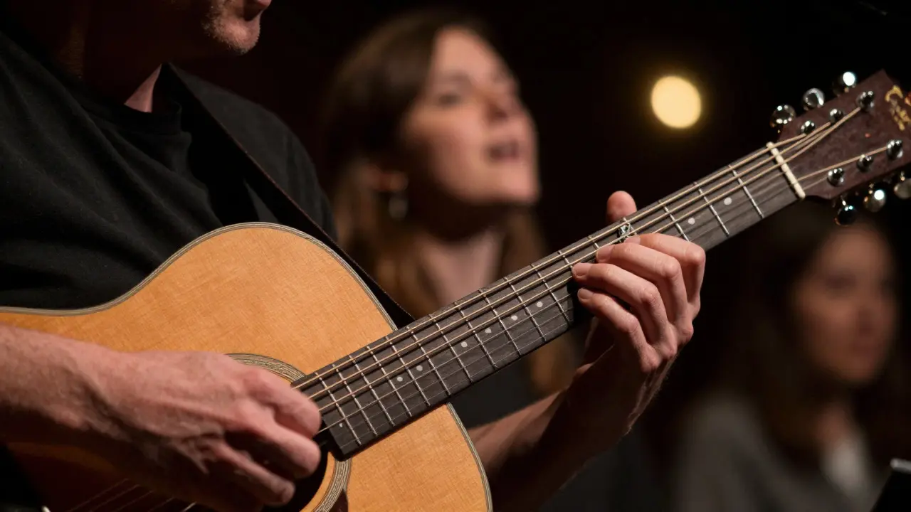 Close-up of guitar strumming hands with a blurred audience member in the background